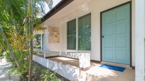 A building with a white exterior, a blue door, and a window with a view of greenery. - Chaiyo Resort Phuket by Zuzu (Wichit)