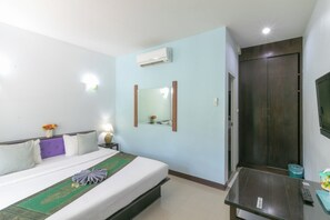 A hotel room with a bed, bedside table, lamp, mirror, air conditioning unit, and a TV. - Chaiyo Resort Phuket by Zuzu (Wichit)