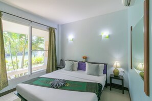 Ein Hotelzimmer mit einem großen Bett, einem Nachttisch mit Lampe, einem Fenster mit Vorhängen und einer Wandleuchte.
