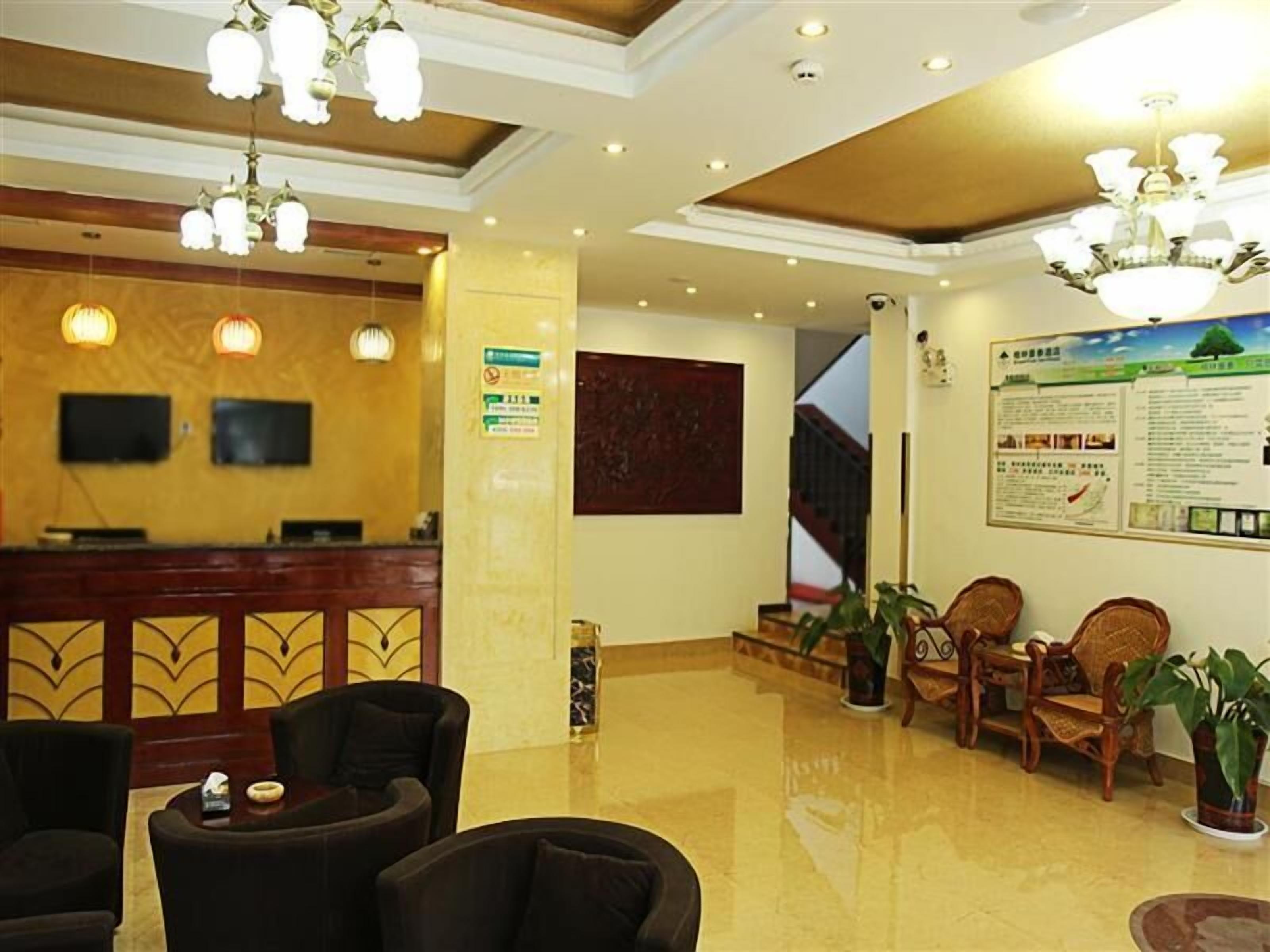 A hotel lobby with a reception desk, seating area, and informational poster.