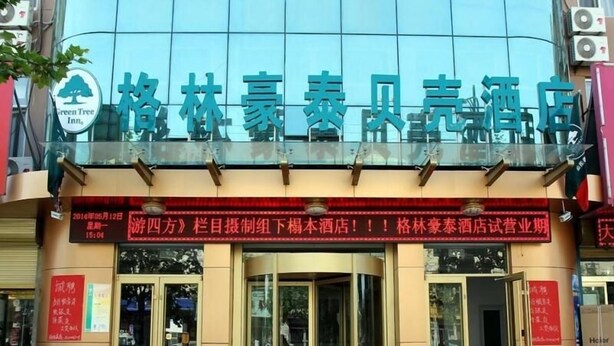 A hotel entrance with glass doors and a red signboard above.