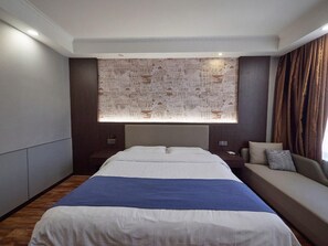 Ein Hotelzimmer mit einem großen Bett, einem Nachttisch, einer Couch und einer Wanddekoration mit Muster.