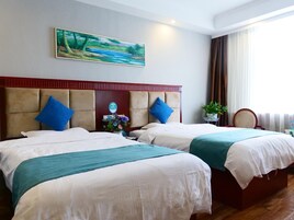 Habitación de hotel con dos camas, un cuadro en la pared, una planta y vistas al exterior.