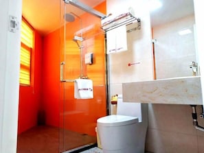 Un bagno con cabina doccia in vetro, un water bianco e un lavabo in marmo.