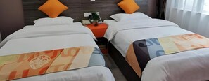 A hotel room with two beds, each with a patterned bedspread. There is a nightstand between the beds with a small plant and a telephone. - Shell Hefei Yaohai Distrct Baida Zhougudui Daxing Road Hotel (Hefei)