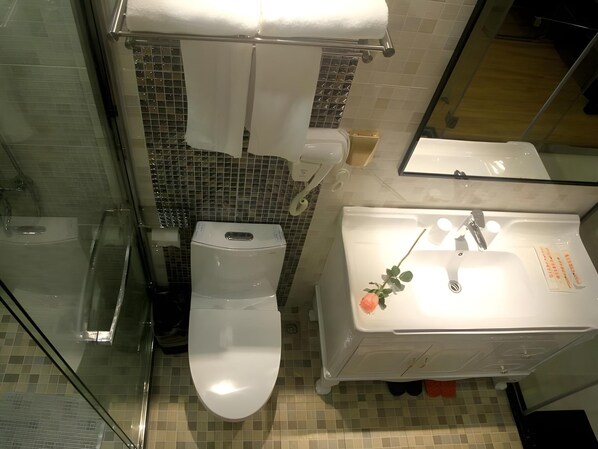 A bathroom with a toilet, sink, and glass shower enclosure.