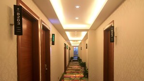 A hotel hallway with wooden doors, numbered signs, and a colorful geometric patterned floor. - Shell Shanghai Pudong New District Zhongke Road Hotel (Shanghai)