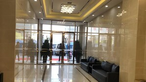 Un hall d'entrée moderne avec une entrée en verre, un comptoir d'accueil et un espace salon.
