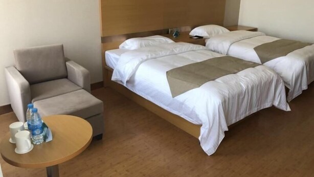 Une chambre d’hôtel avec un lit, une chaise, une petite table et un mur orné de motifs circulaires.