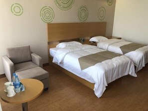 A hotel room with a bed, a chair, a small table, and a wall with circular patterns. - Greentree Inn Xi'an Gaoling District Handan Industrial Park Express Hotel (Xi'an)