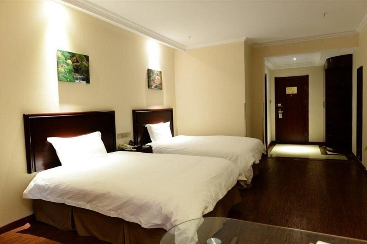 A hotel room with two beds, a glass table, and a wooden floor.