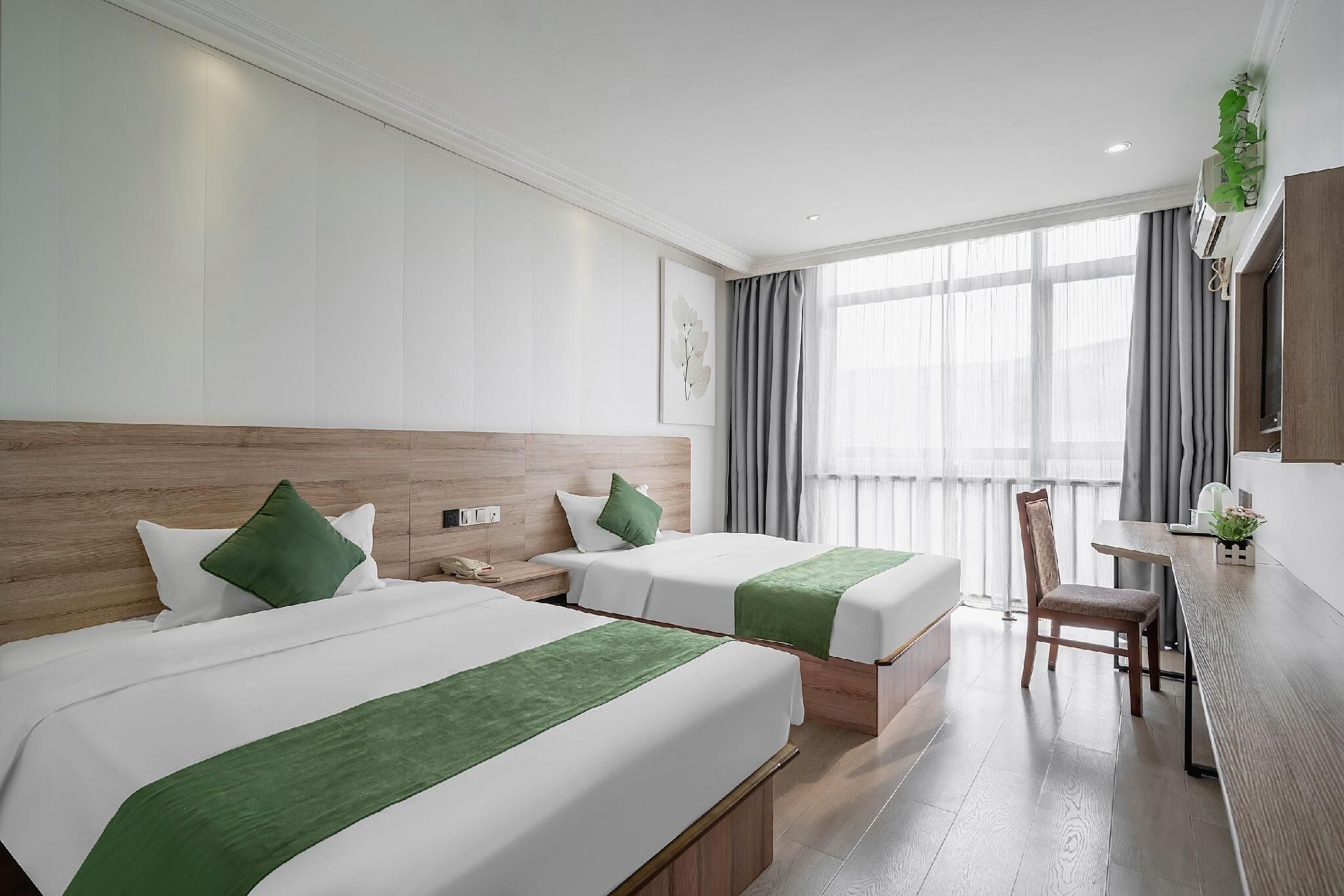 A hotel room with two beds, a desk, and a chair.