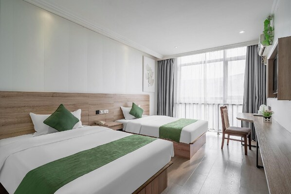 A hotel room with two beds, a desk, and a chair.