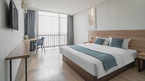 A modern hotel room with a large bed, a desk with a chair, a TV, and a balcony with curtains. - Greentree Inn Suzhou Huqiu West Chengbei Road Fulin Square Express Hotel (Suzhou)