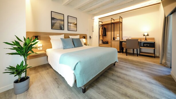 Une chambre d’hôtel moderne équipée d’un lit, de tables de chevet, d’un bureau et d’une armoire.