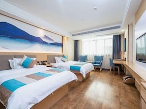 A hotel room with two beds, a desk, and a large window.