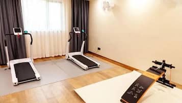 Una habitación con dos cintas de correr, una bicicleta estática y una máquina de remo.