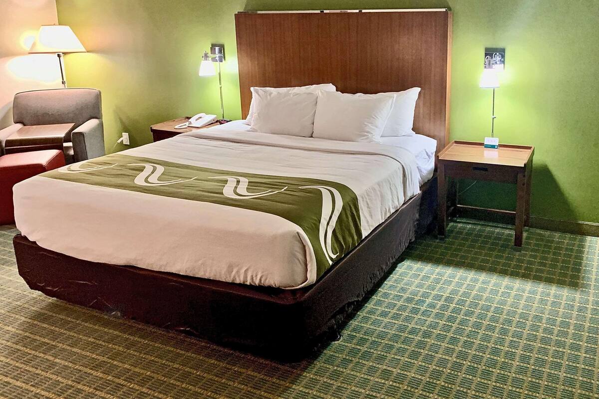 Ein Hotelzimmer mit einem großen Bett, grünen Wänden und zwei Nachttischen mit Lampen.