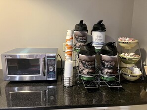 A commercial microwave oven, a water dispenser, and a coffee maker on a kitchen counter.
