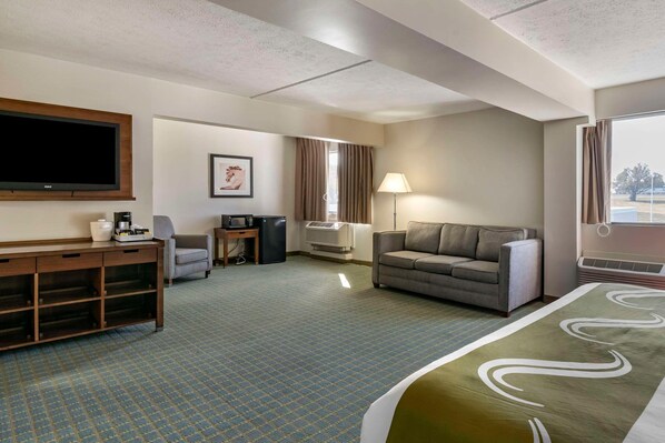 A hotel room with a flat-screen TV, a sofa, a desk with a computer, a lamp, and a large window. - Quality Inn Lexington -horse Park (Lexington)