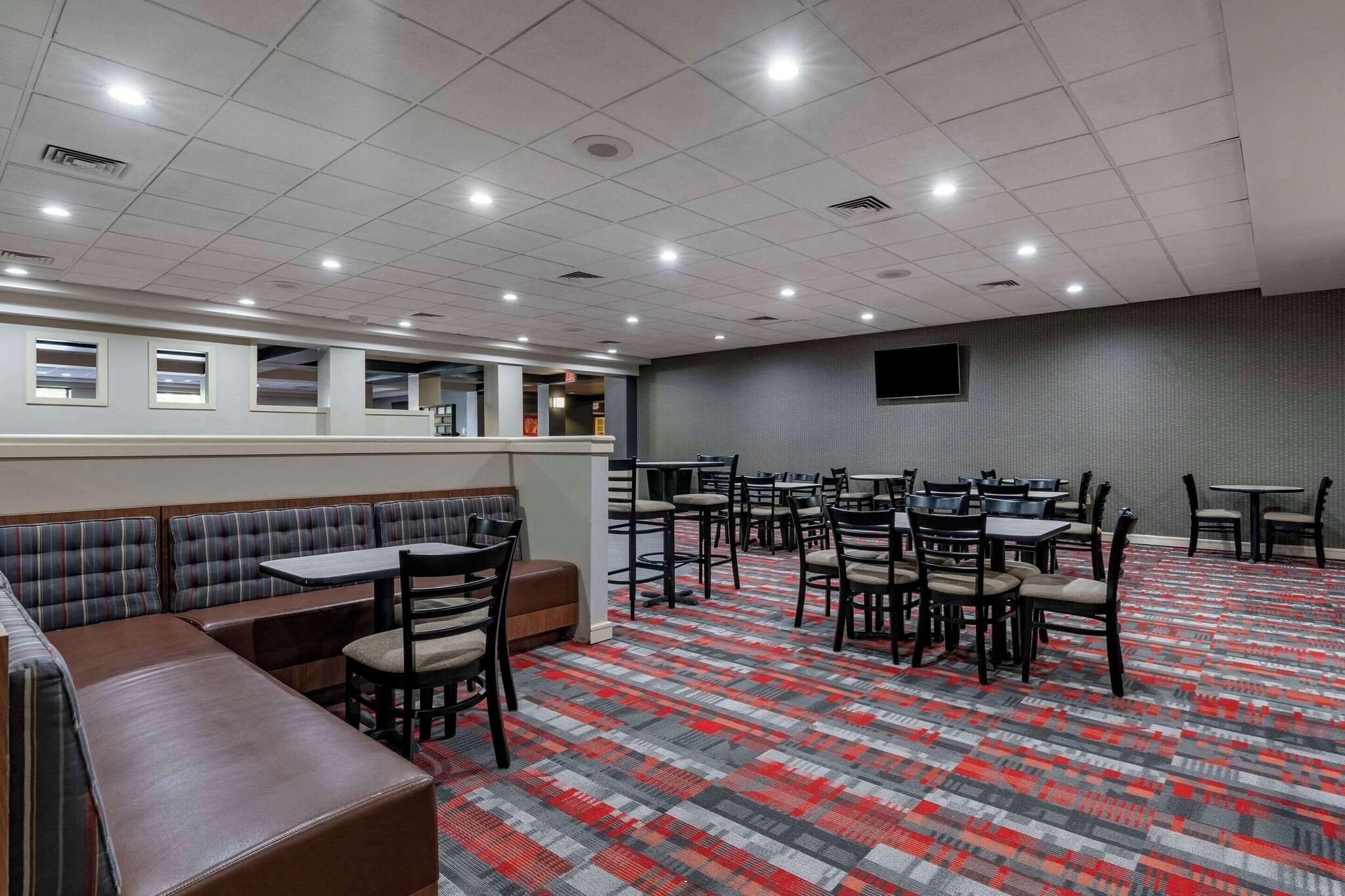A hotel dining area with booths, tables, and chairs.