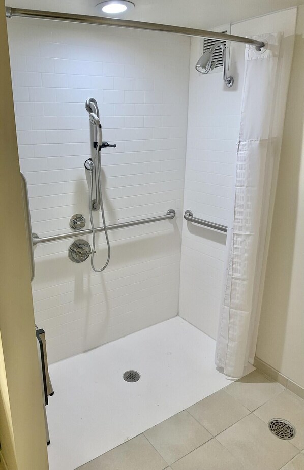 A shower area with white tiled walls, a showerhead, a handheld shower, and a curtain. - Quality Inn Lexington -horse Park (Lexington)