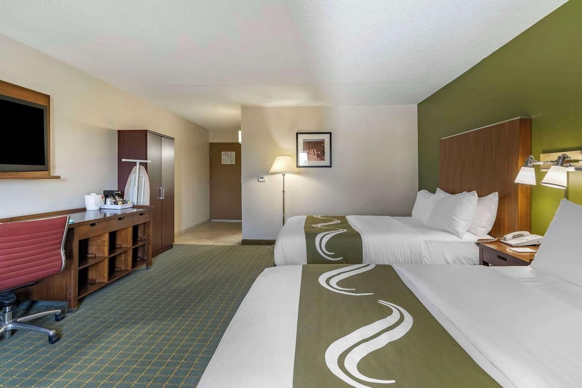 Ein Hotelzimmer mit Bett, Schreibtisch, Stuhl, Kleiderschrank und Lampe.