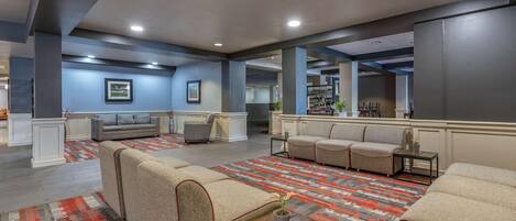 A spacious lobby with sofas, a patterned carpet, and a bar area.
