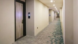 A long, narrow hallway with a patterned carpet and a series of doors on one side. - Greentree Inn Zaozhuang Tengzhou Fuqian Road Longquan Square Business Hotel (Zaozhuang)
