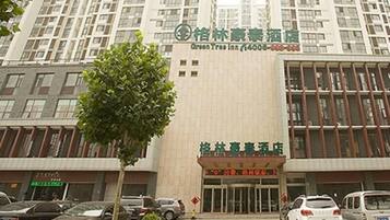 A hotel with a modern facade, multiple floors, and a parking lot with several cars.