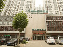 Un hotel con fachada moderna, varios pisos y un estacionamiento con varios coches.