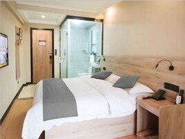 Una habitación de hotel con cama, mesita de noche y espejo.