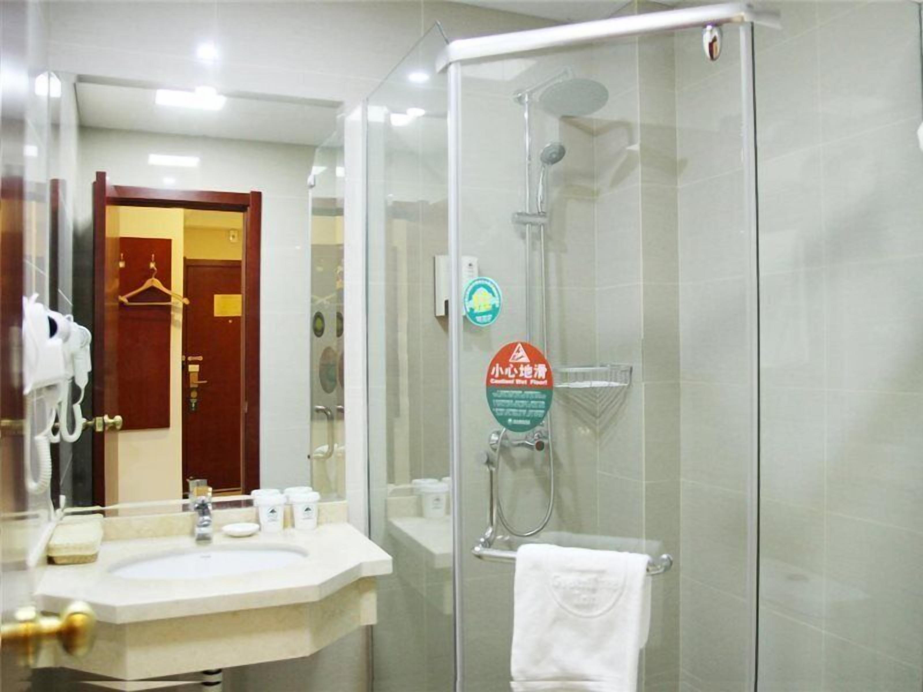 A modern bathroom with a glass-enclosed shower, a sink with toiletries, and a mirror.
