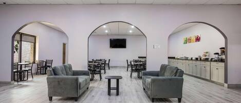 A spacious lounge area with sofas, tables, and a kitchen area.