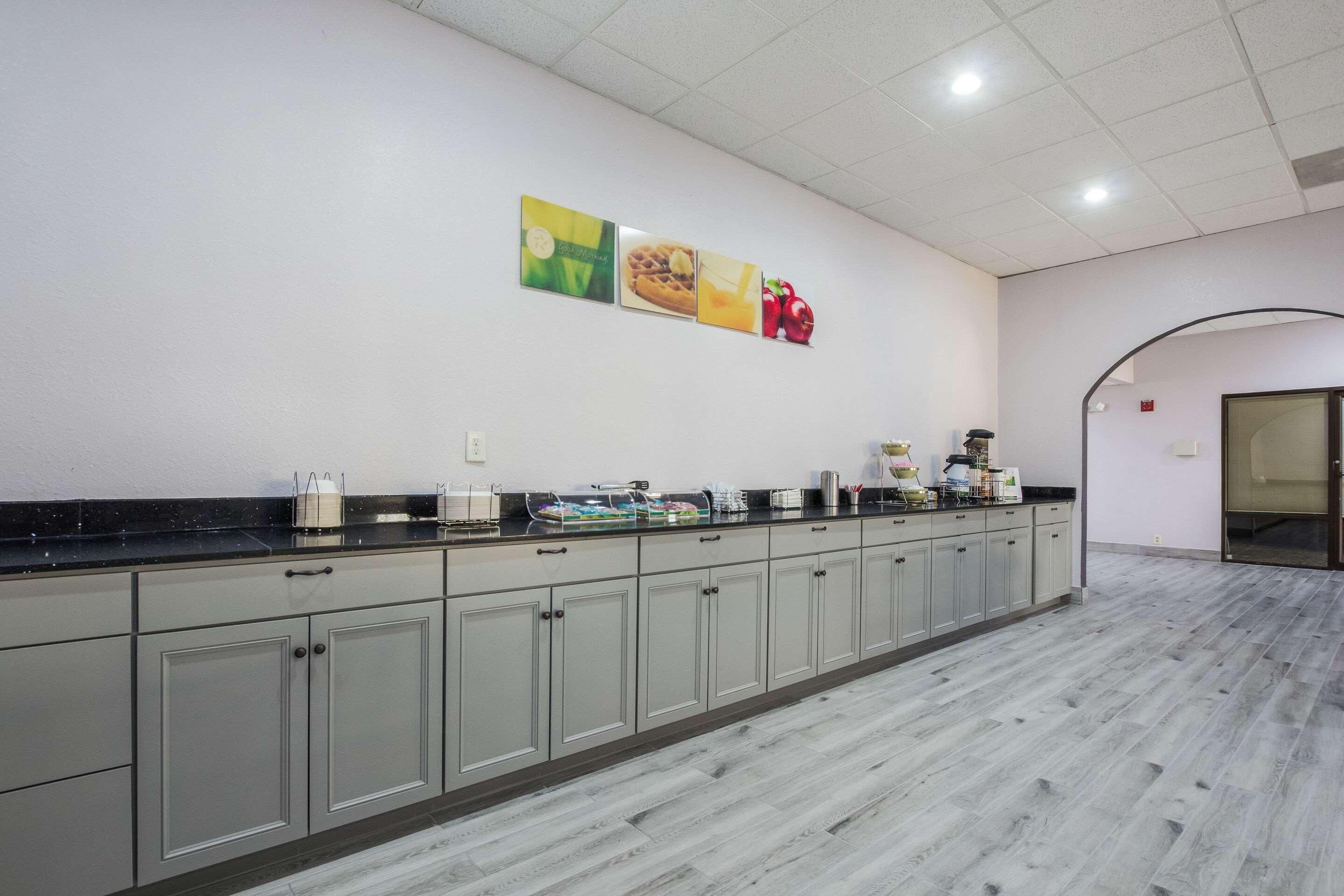 A kitchen with a long counter, cabinets, and a wall-mounted coffee station.