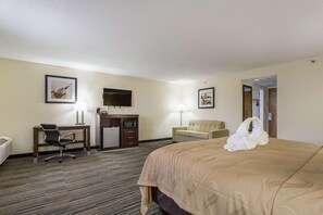 A hotel room with a bed, a desk with a chair, a television, a sofa, and a framed picture on the wall. - Quality Inn Grayville (Grayville)