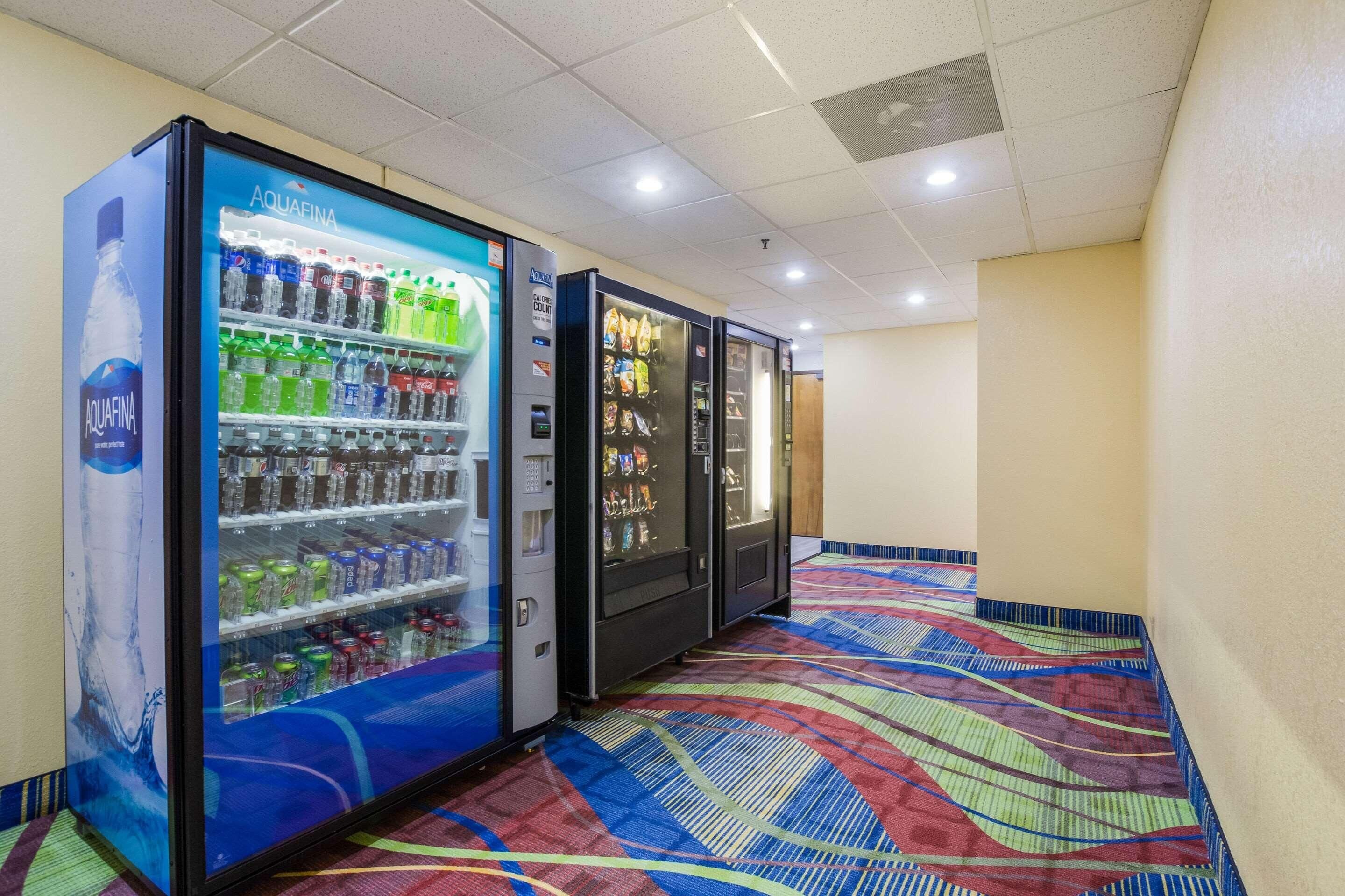 A row of vending machines in a hallway with a patterned carpet.