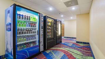 A row of vending machines in a hallway with a patterned carpet.