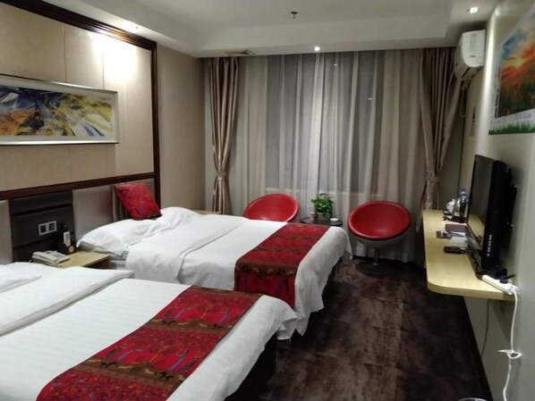 A hotel room with two beds, a TV, a desk, and a red chair.