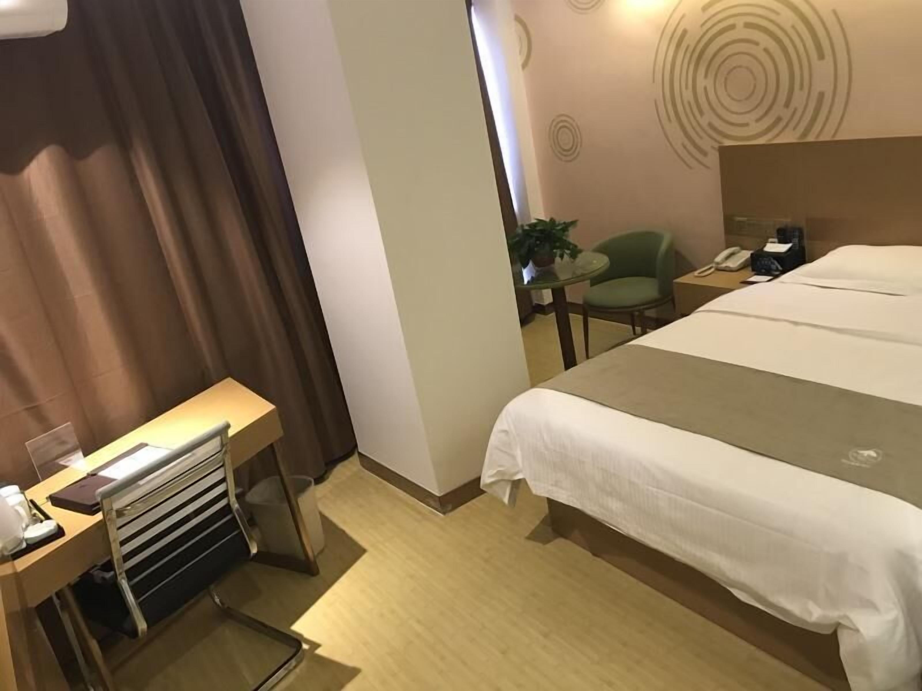 A hotel room with a large bed, a desk with a chair, a small table with a chair, and a telephone.