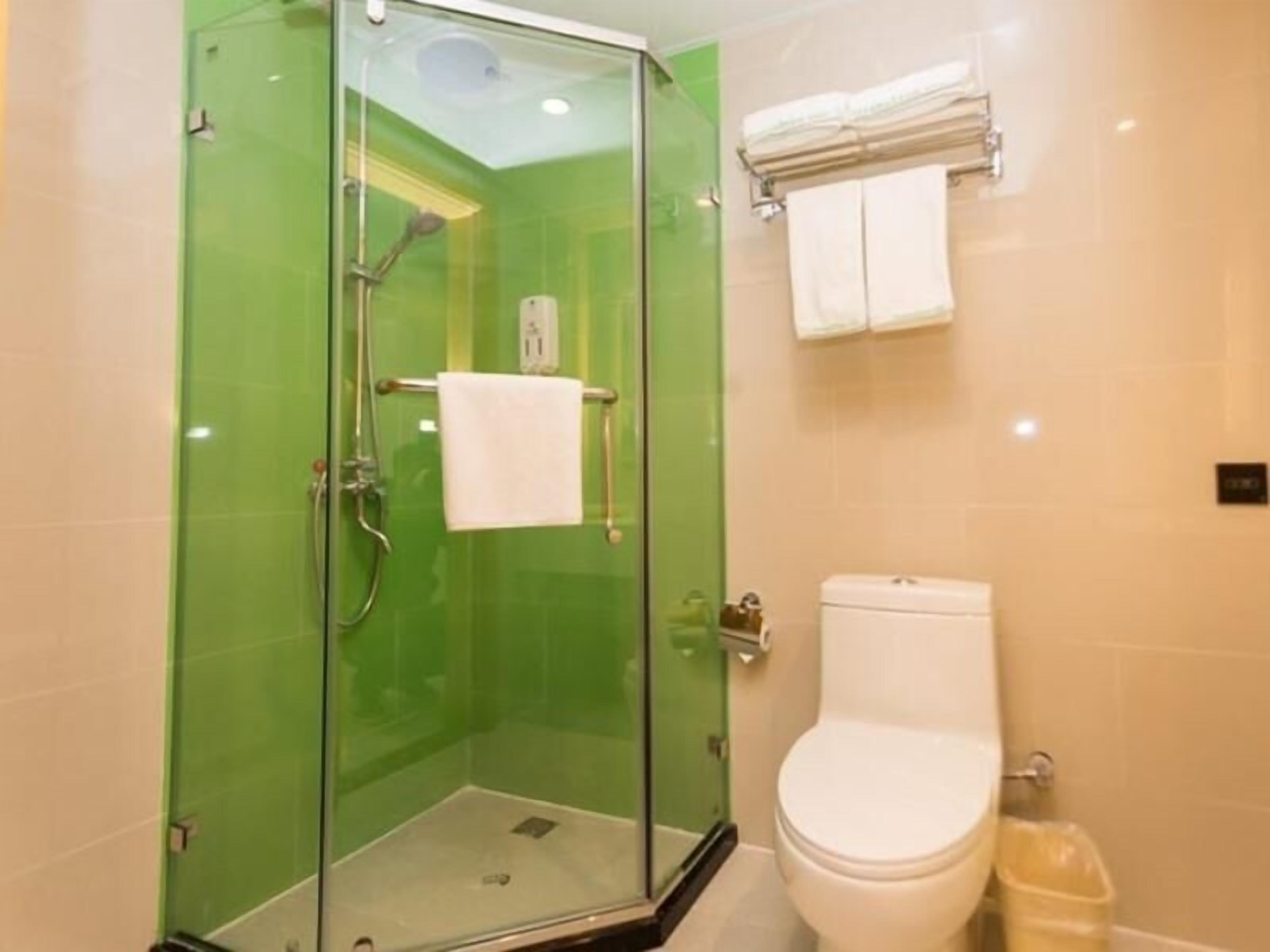 A bathroom with a glass-enclosed shower, a white toilet, and a towel rack with a white towel.