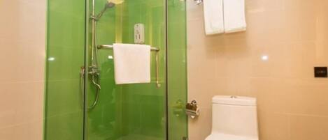 Un baño con ducha de mampara de vidrio, inodoro blanco y toallero con una toalla blanca.