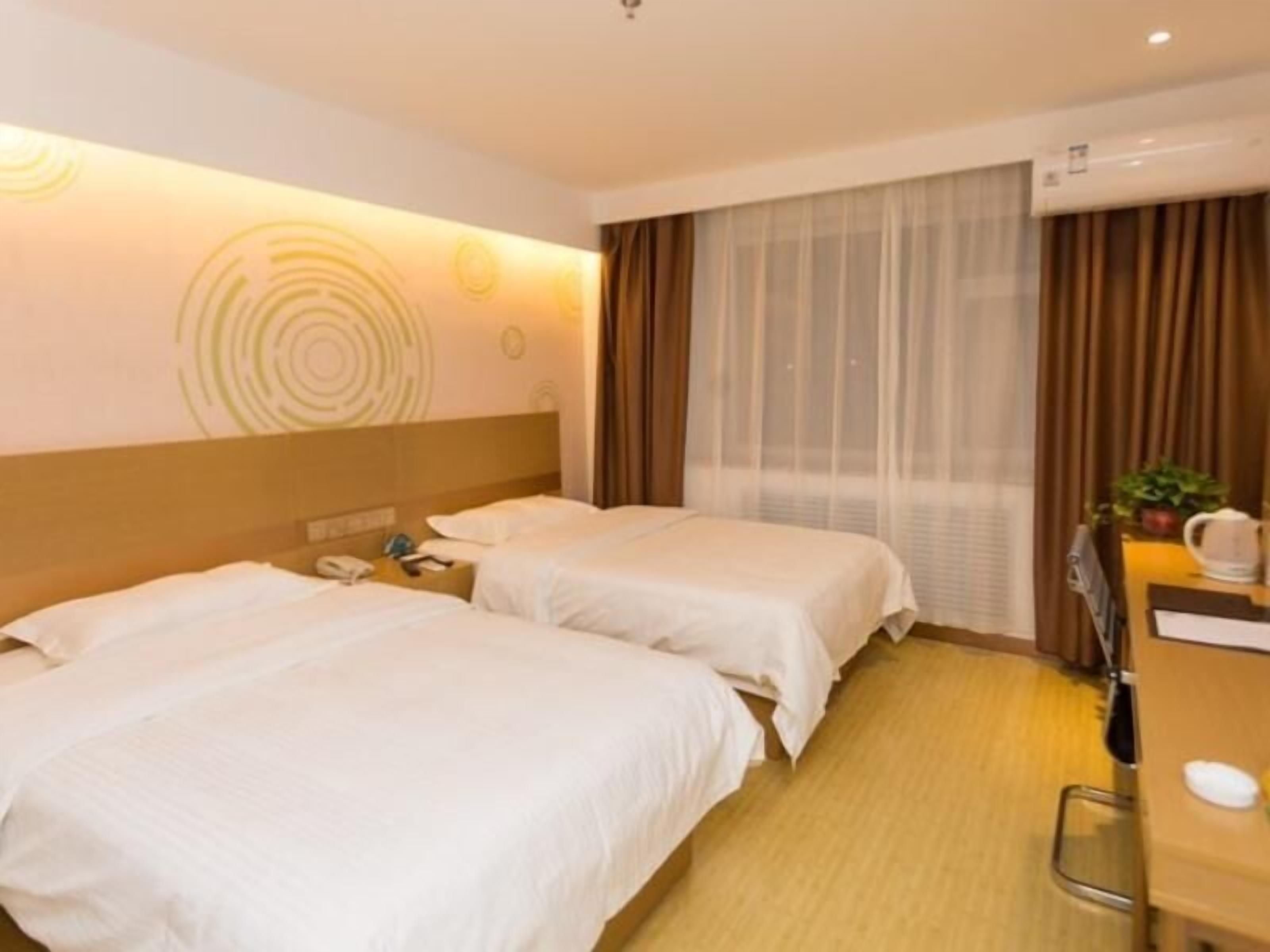 A hotel room with two beds, a desk, a chair, a telephone, and a window with curtains.