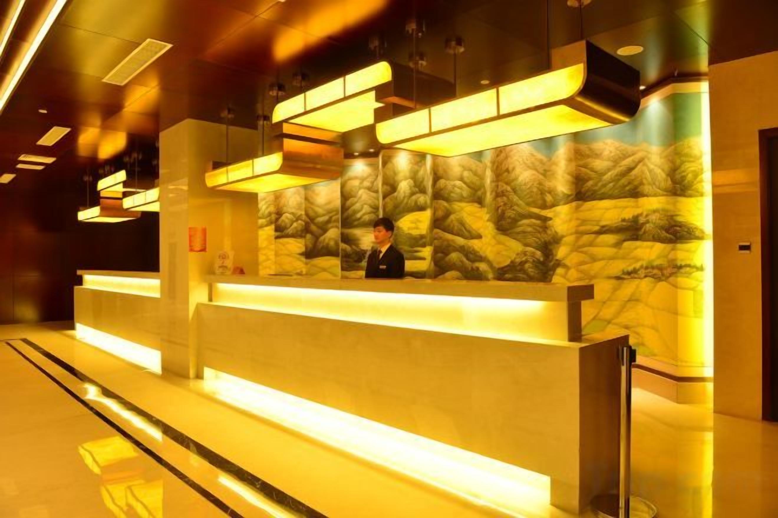 A reception desk with a stone wall backdrop, a modern light fixture, and a clean, polished floor.