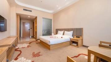 A modern hotel room with a wooden bed, bedside tables, a desk, and a chair.