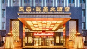 A hotel entrance with a traditional architectural design, featuring a prominent entrance canopy and decorative elements. - Min Le Long Xin Hotel (Minle)
