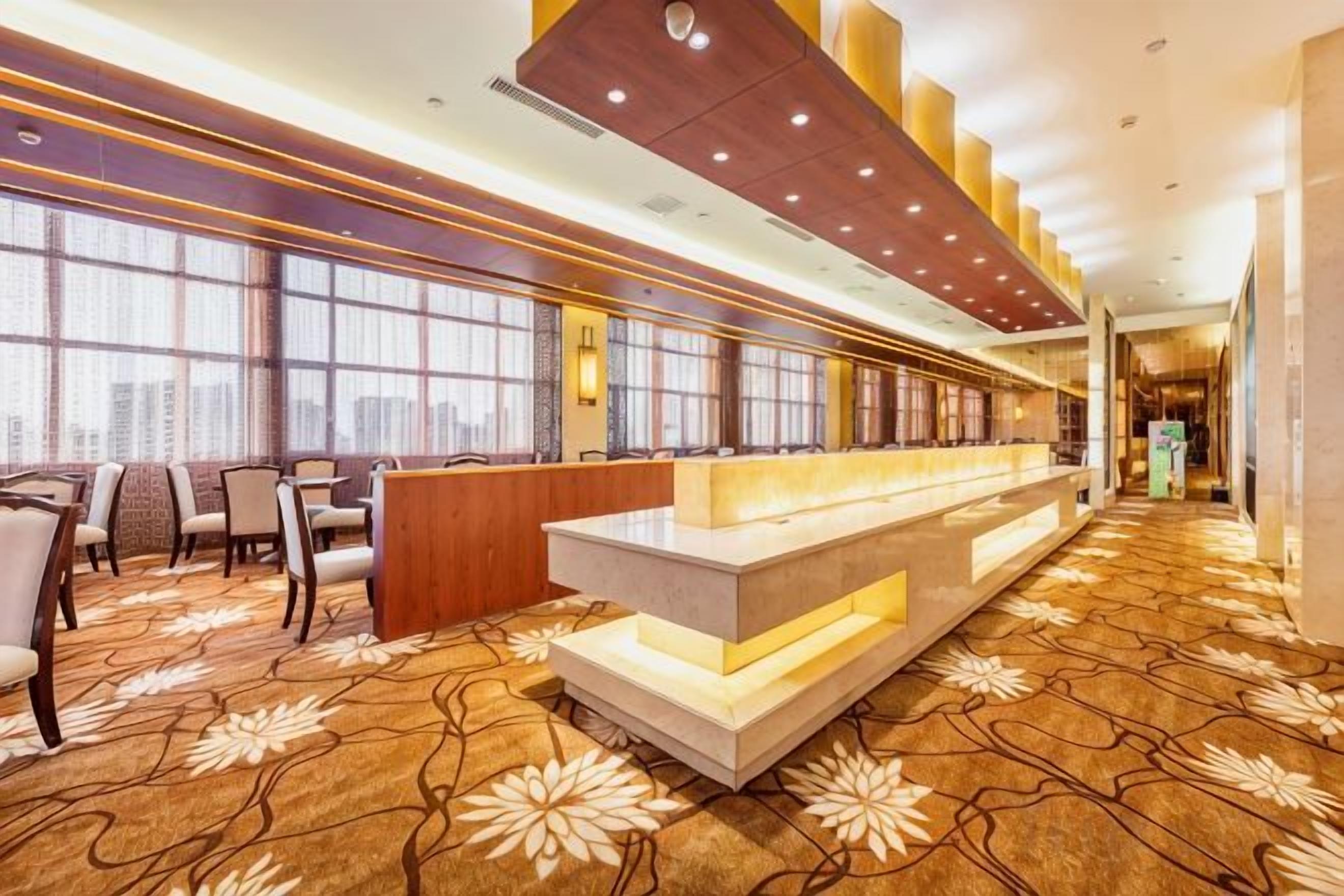 A hotel lobby with a reception desk, seating area, and large windows offering city views.