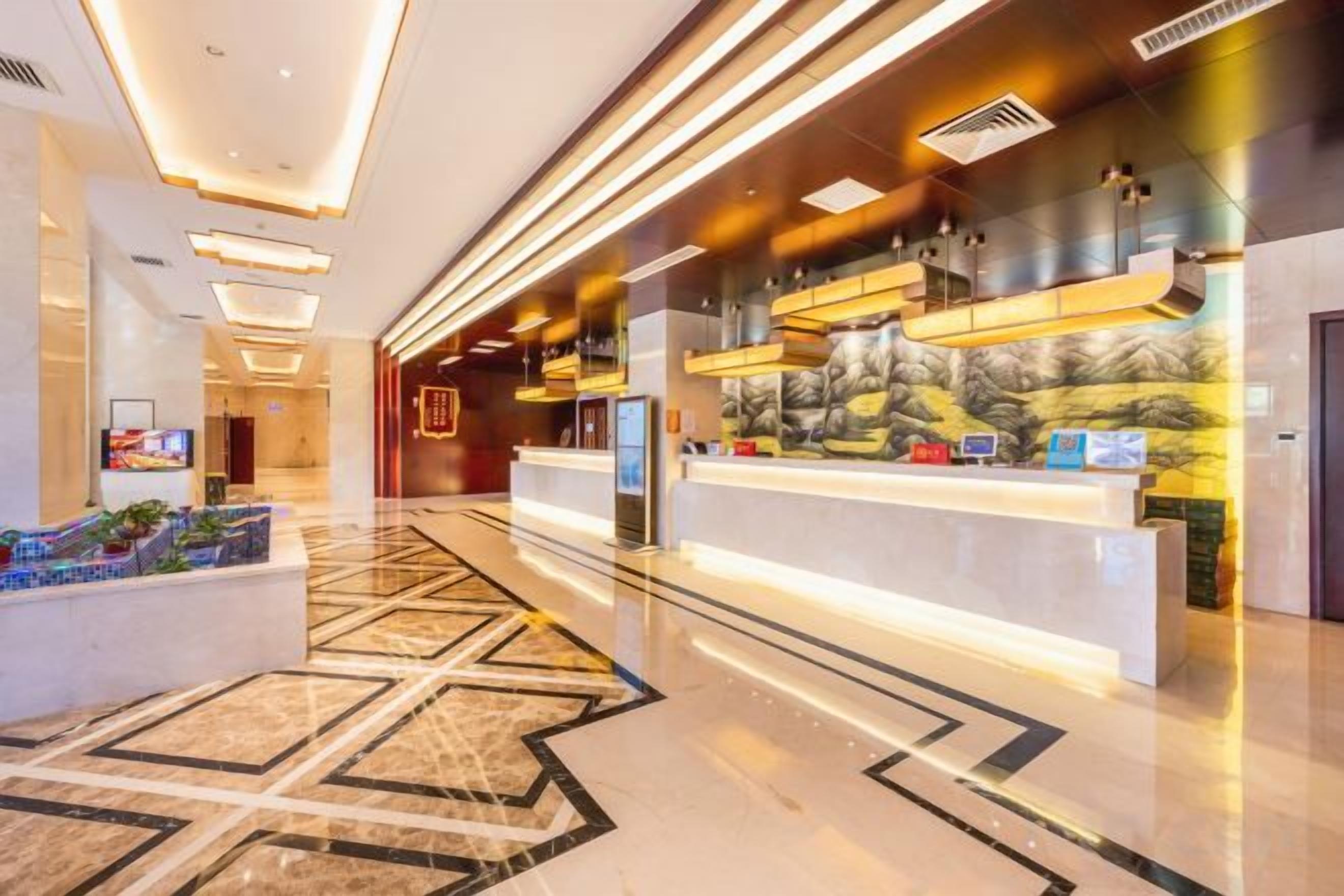 Una hall d'albergo con reception, area relax e pavimento decorato.