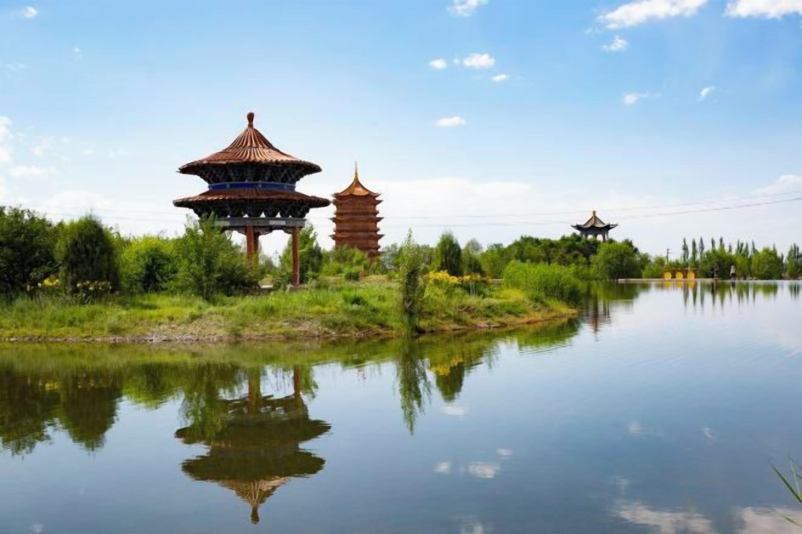 Ein traditionelles Pagodengebäude mit Spiegelung in ruhigem Wasser, umgeben von viel Grün.