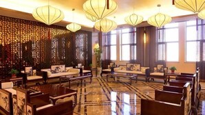 A hotel lobby with traditional decor, including patterned walls, wooden furniture, and hanging lanterns. - Min Le Long Xin Hotel (Minle)